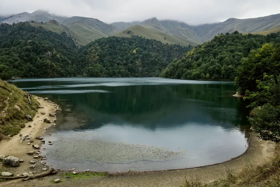 A still blue lake ringed by forested slopes at Goygol.